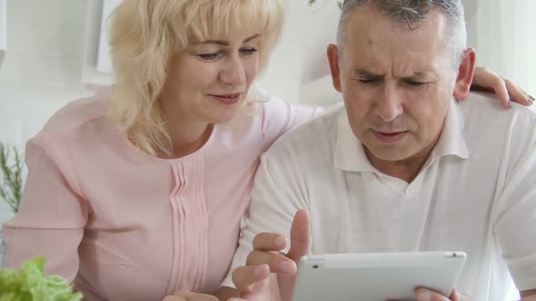 Mature Married Couple Learning To Use Tablet Computer