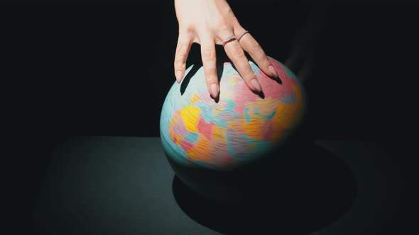 Girl's Hands Twist the Geographic Globe Around Its Axis