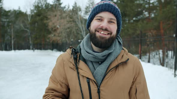 Portrait of Handsome Young Man Standing Outdoors in Park on Winter Day