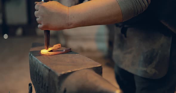 Blacksmith Holds a Horseshoe in Tongs and Knocks with a Hammer