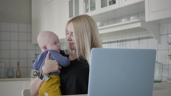 Mother Taking Care Her Baby While Working At Home