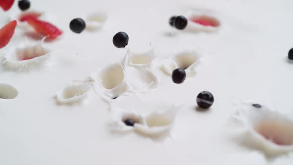 Tossing cut strawberries, blueberries and raspberries in yoghurt. Slow Motion.