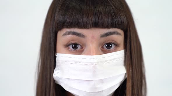 A young girl with protective mask  look at camera. Coronavirus icon. Close up shot.