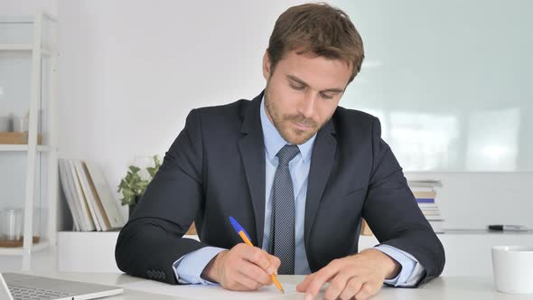 Businessman Writing Documents in Office