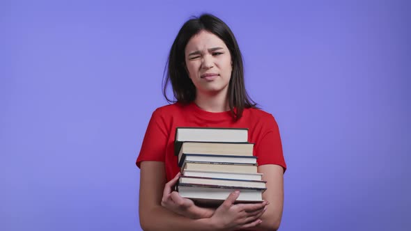 Asian Student is Dissatisfied with Amount of Homework and Books on Violet Background