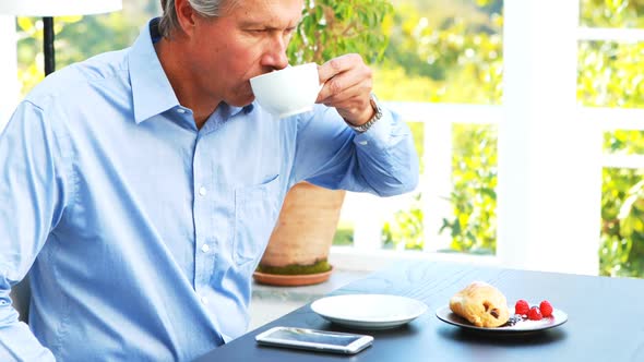 Businessman talking on mobile phone and drinking coffee in restaurant