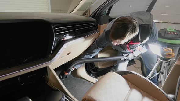 Man Using the Vacuum Cleaner Inside the Car Removing Dust and Dirt From Cloth Floor Mats