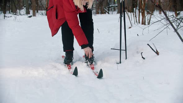 A Young Blonde Woman in Red Down Jacket Unsetting Her Boots From the Ski