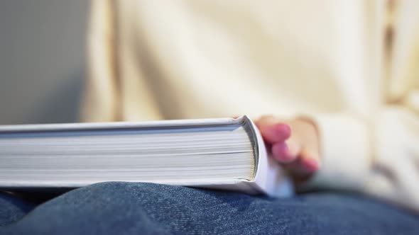 A Woman Puts a Big White Book on Her Feet