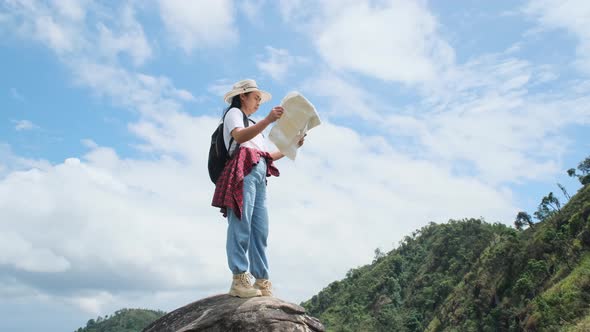 Backpacking female hiker stands on top of the mountain and enjoying the view.