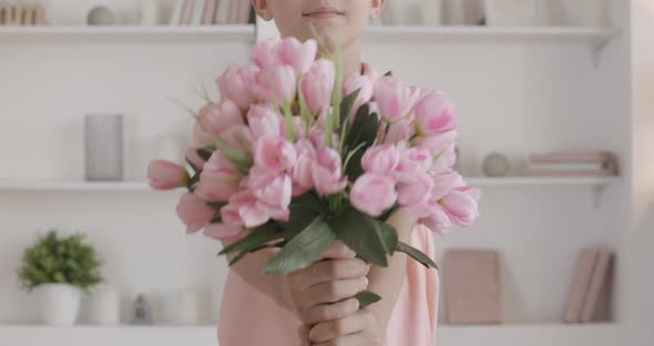 Unrecognizable Boy Stretching Bouquet of Pink Tulips at Camera. Polite Caucasian Kid Coming