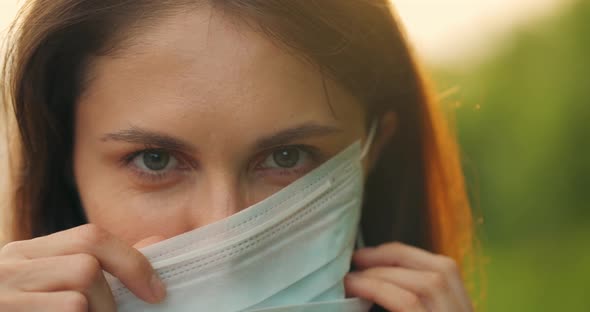 Young Beautiful Girl Puts Protective Protective Medical Mask on Her Face