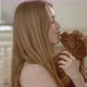 A poodle puppy licks the face of a young beautiful girl while she holds it in front of her face - VideoHive Item for Sale
