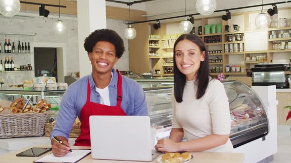 Video of happy diverse female owner and male waiter at cafe shop