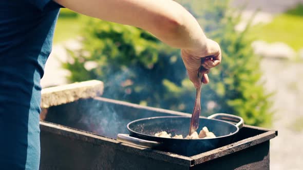 Close-up, Slow Motion: Man Cooks Pilaf, in Cauldron, on Coals, on a Grill. Stir the Meat