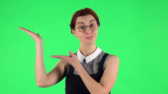 Portrait of Funny Girl in Glasses Is Pointing Side Hand for Something Then Nods and Showing Thumb Up