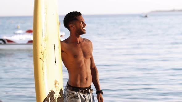 Portrait of Young Professional Black Surfer Man Holds His Surfboard in Arm Stands on Ocean Beach