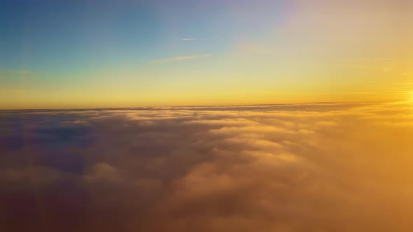 Flying Into the Clouds Illuminated in Orange By the Suns Rays at Sunset