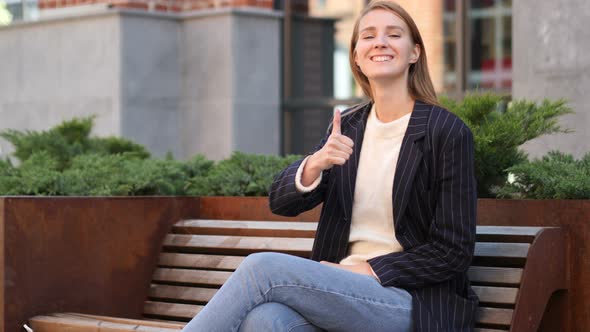 Thumbs Up by Successful Business Woman Sitting on Bench