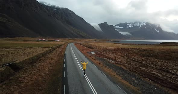 Aerial shot of happy man running on empty road in Iceland