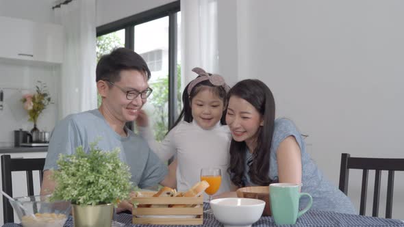 Parent and daughter eating Cereals with milk having breakfast morning in kitchen.