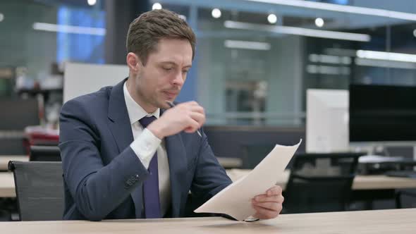 Businessman Reading Documents While Sitting in Office