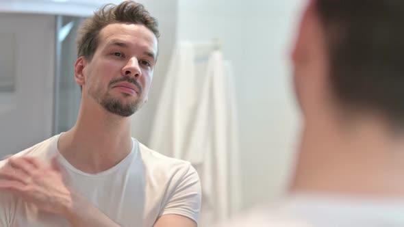 Confident Cheerful Young Man Smiling at Mirror