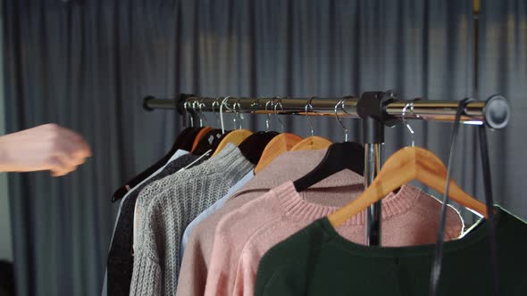 Close Up of Woman Takes a Gray Sweater From a Hanger with Clothes