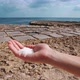 A hand holding salt in front of saltpans by the sea - VideoHive Item for Sale