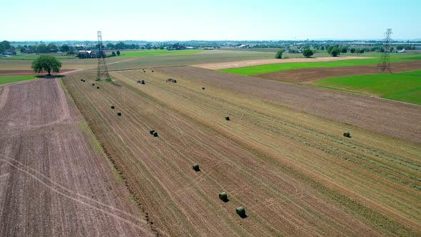 Amish Farm Worker Harvesting the Fields with old and New Equipment