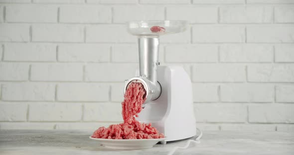 Raw Mincemeat Falls From a Meat Grinder Into a Plate. 