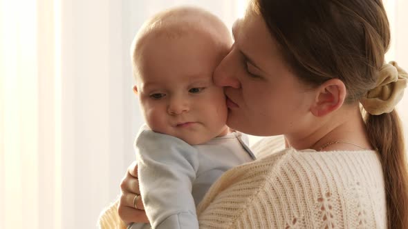 Portrait of Smiling Happy Mother Kissing Her Little Baby Son in Cheeks