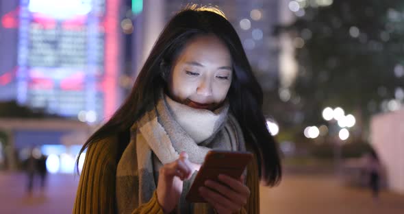 Woman working on cellphone in the city at night