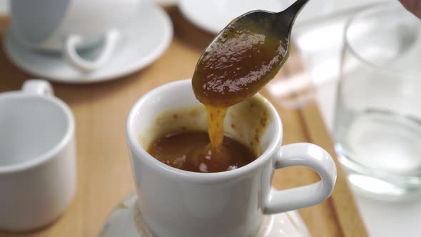 Fig jam with seeds in a teaspoon. Stirring homemade dessert in a white cup on the kitchen table