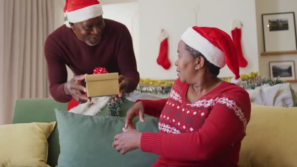 Happy senior african american man giving gift to his wife