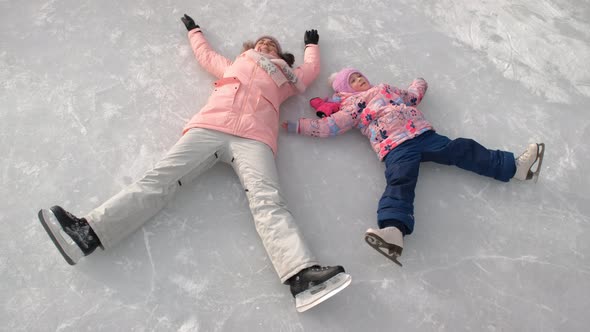 Woman with Daughter Having Fun While Lying on Ice