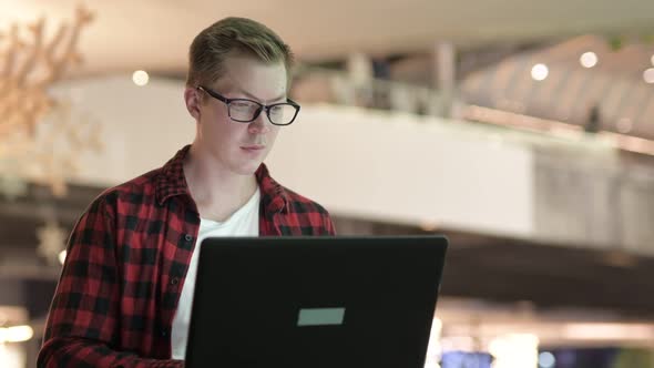 Young Handsome Hipster Man Smiling While Using Laptop In The City At Night