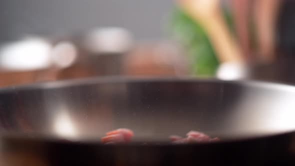 Camera follows cooking bacon in a pan. Slow Motion. alt