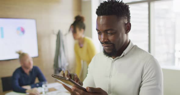 Portrait of happy african american businessman with tablet in creative office