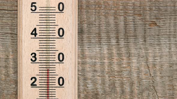 Increasing temperature on wooden thermometer with red scale