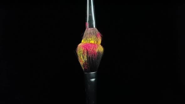 Makeup Brushes Touch Each Other on Black Dark Background and Small Particles of Color Cosmetics