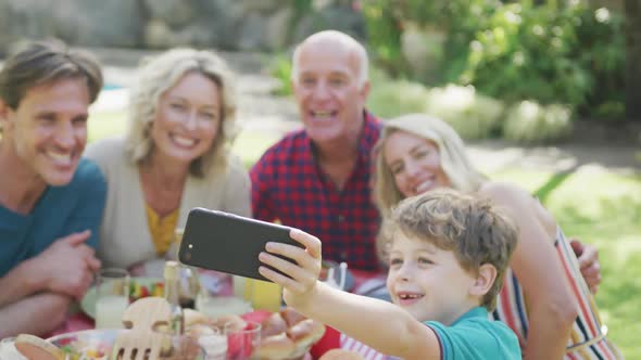 Happy caucasian family having dinner and taking selfie in garden