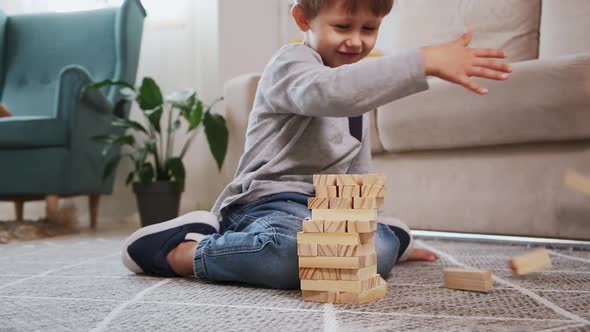 Child Crash Wooden Jenga Tower Sitting on Floor at Home