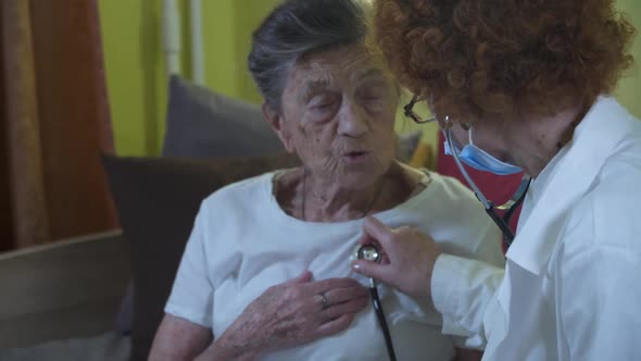 Elderly Caucasian Woman Doctor Listening To Elderly Patient Breathing Medical Exam with Stethoscope