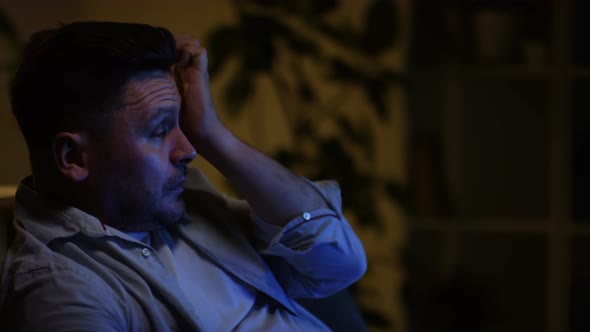 Man Crying During Movie in Dark Room