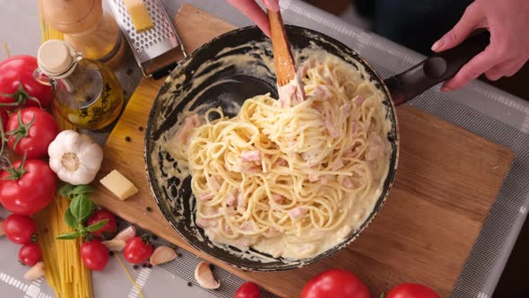 Making Pasta Carbonara Mixing Spaghetti and Sauce Made of Cream and Chopped Pancetta Bacon in Frying