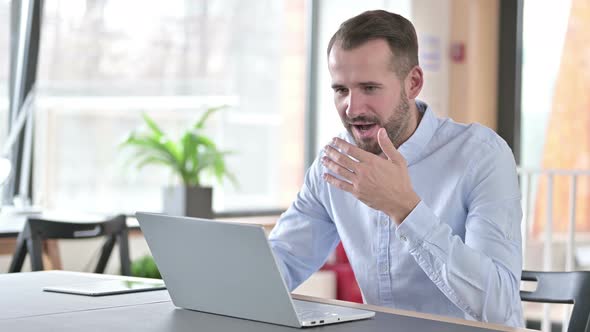 Young Man Celebrating Success on Laptop in Office 