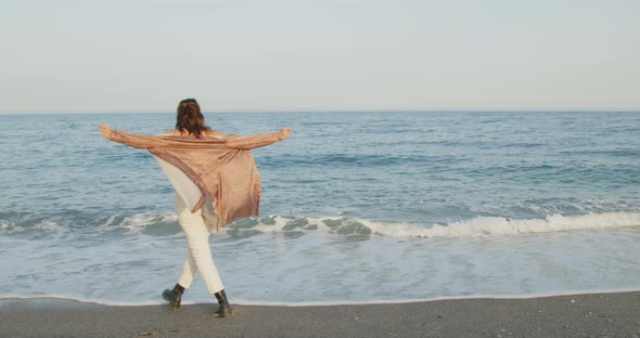 Young girl with black boots has fun on the beach near the sea in Italy