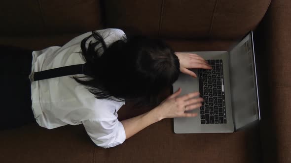 Young Woman Using Laptop at Home Sitting on Sofa