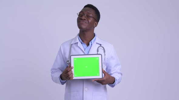 Young Happy African Man Doctor Thinking While Showing Digital Tablet